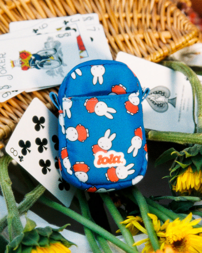 Miffy camera pouch on a picnic basket with playing cards and sunflowers